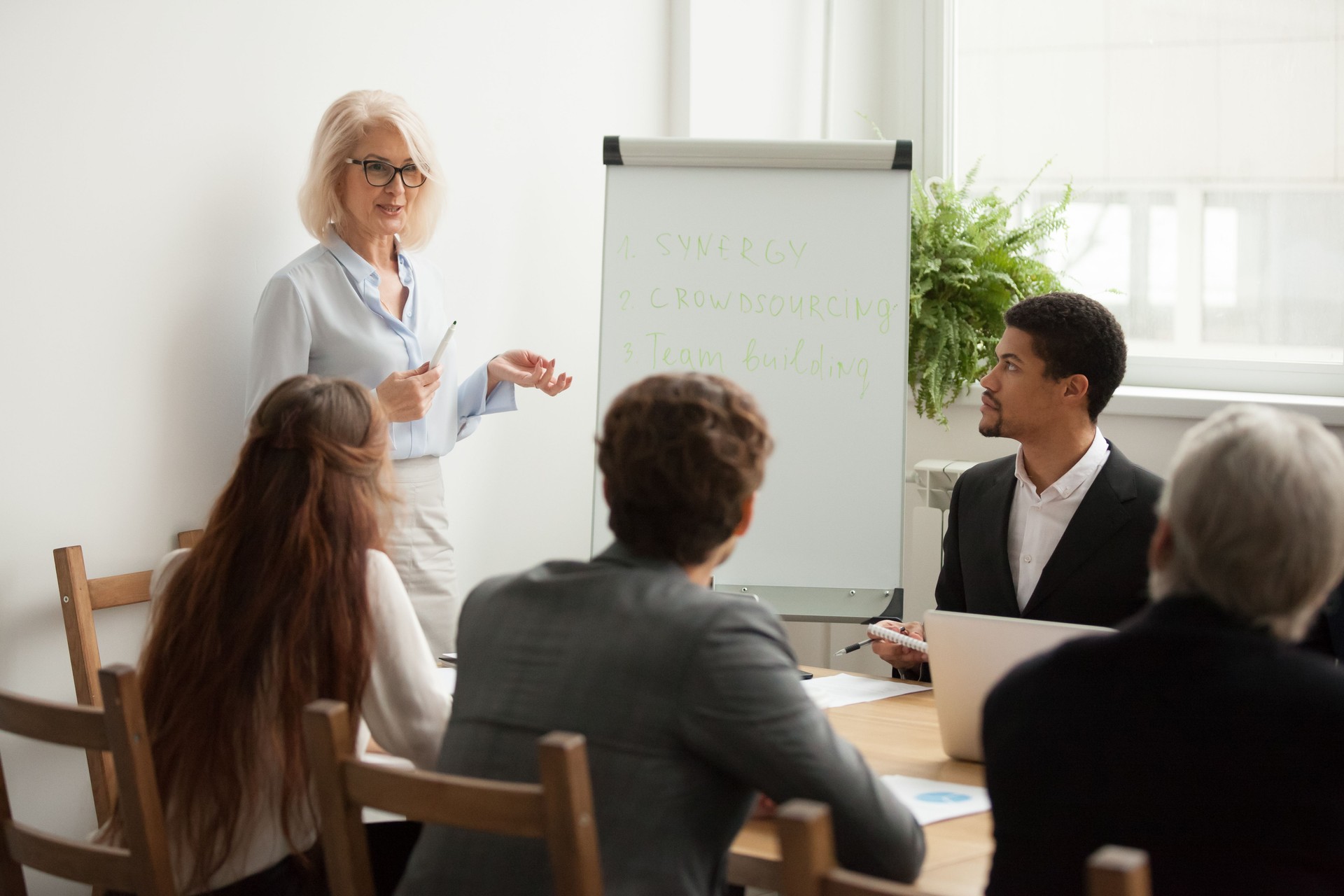 Aged attractive businesswoman giving presentation at corporate team meeting